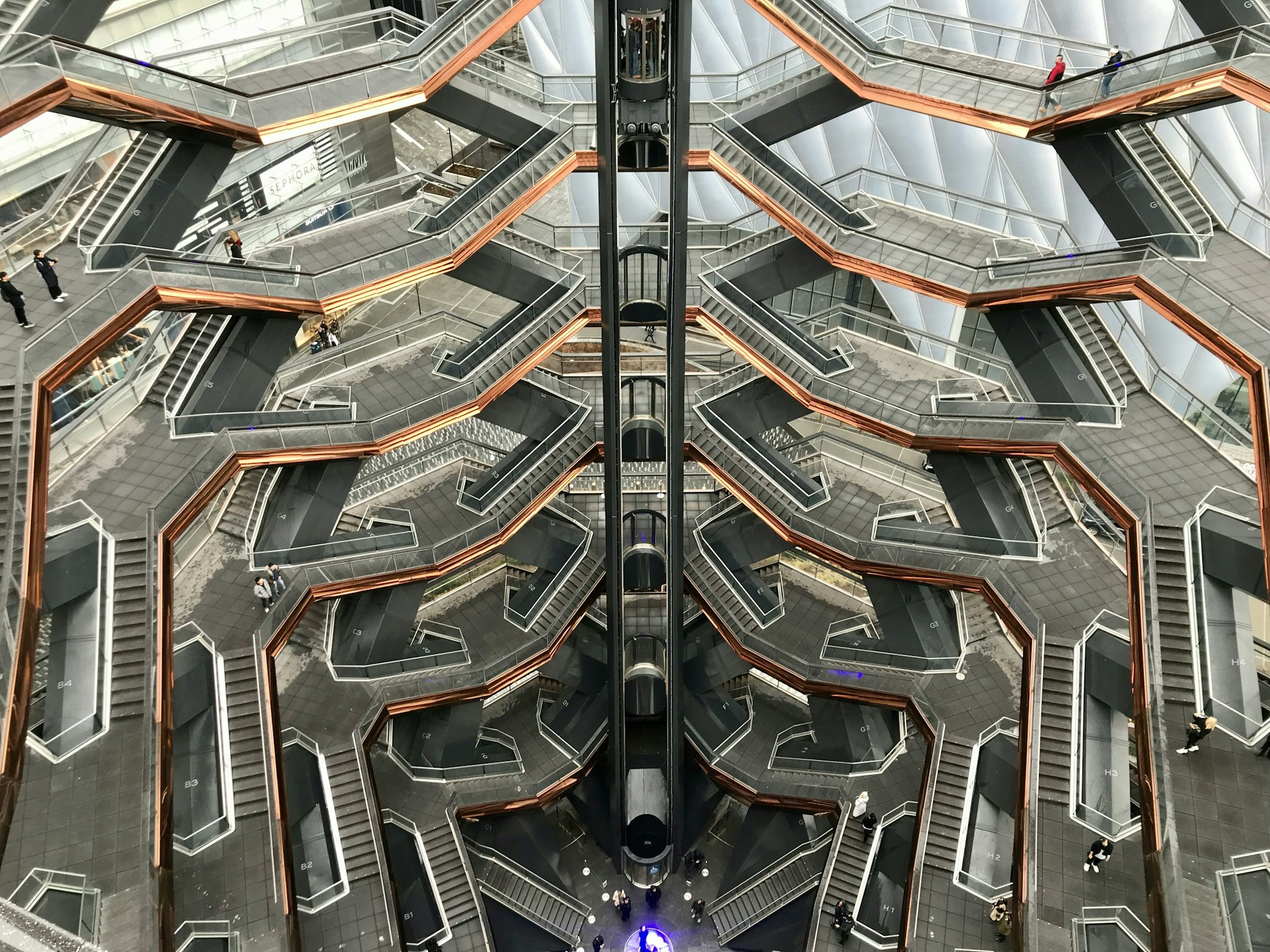 A honeycomb-like construction of stair fights rising to landings where people are standing.